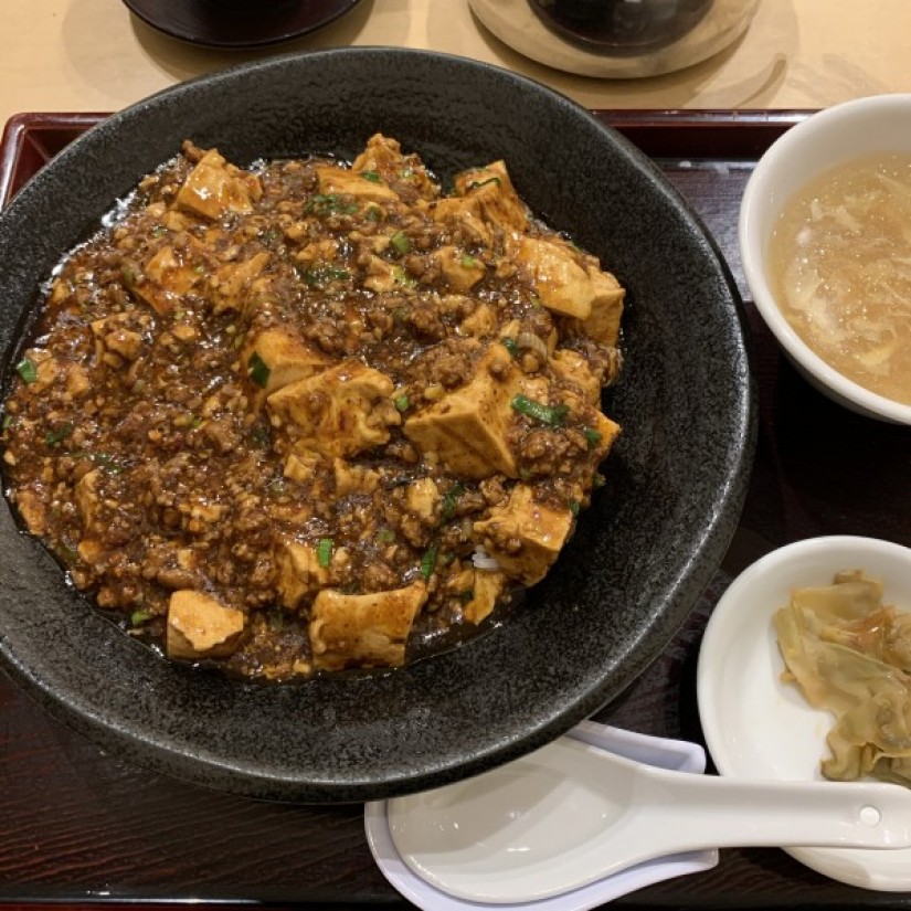 麻婆豆腐丼 辛さ絶品！麻婆豆腐 豆腐・挽肉・白葱。たったこれだけの食材に、大蒜・豆板醤・甜面醤・辣椒粉・豆鼓・辣油などの四川自慢の調味料を強い火力で熱々に仕上げました。舌も心もしびれる逸品です。しかも、毎月十二日は「豆腐の日」で半額で提供いたします。