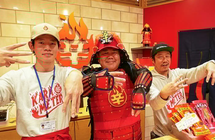 辛メーターポーズをする三人。左から店長・野口くん、辛メーターのオリジナル甲冑を着たゴリけんさん、辛メーター代表の江口カン。